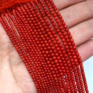 May include: Strands of small, round, bright red beads. The beads are tightly strung together, creating a dense, textured appearance. The color is a vibrant, saturated red, and the beads have a slight sheen. The beads are likely for jewelry making.