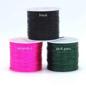 Puede incluir: Tres carretes de cord&oacute;n el&aacute;stico en negro, rosa intenso y verde oscuro. Los carretes est&aacute;n etiquetados con el color del cord&oacute;n.