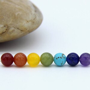 May include: Seven round gemstone beads in a rainbow color sequence. The beads are red, orange, yellow, green, blue, indigo, and violet.