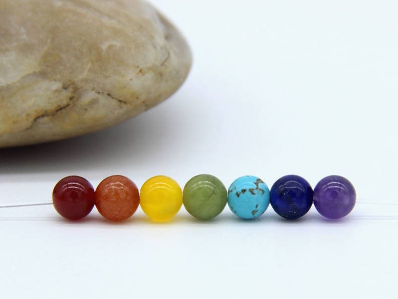 May include: Seven round gemstone beads in a rainbow color sequence. The beads are red, orange, yellow, green, blue, indigo, and violet.