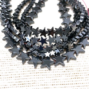May include: A strand of black star-shaped hematite beads. The beads are faceted and have a shiny, metallic finish.
