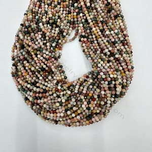 May include: A strand of multi-coloured gemstone beads. The beads are small and round, with a faceted finish. The colours include pink, green, brown, and white.