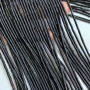 Könnte beinhalten: Eine Schnur schwarzer Röhrenperlen aus natürlichen Materialien zum Schmuckmachen.