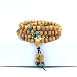 May include: A wooden prayer bead mala with turquoise beads. The mala is made of sandalwood and has a tassel.