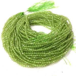 May include: A strand of green peridot beads, faceted and round, strung on a thin thread. The beads are small and uniform in size, creating a smooth and consistent look.