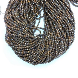 Puede incluir: Una hebra de cuentas de piedra preciosa facetada marrón. Las cuentas son pequeñas y tienen una superficie rugosa y texturizada. Las cuentas están enhebradas en un hilo transparente.