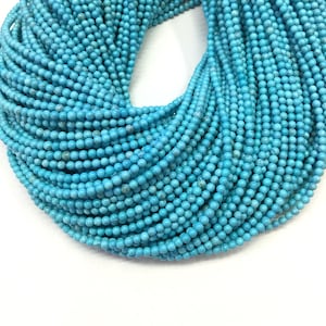May include: A strand of turquoise blue round beads. The beads are small and uniform in size. The strand is coiled and the beads are tightly packed together.