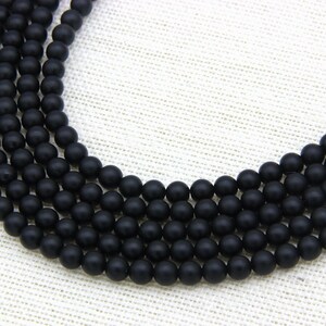 May include: A strand of black matte round beads. The beads are uniform in size and have a smooth, polished finish.