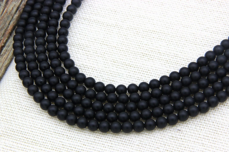 May include: A strand of black matte round beads. The beads are uniform in size and have a smooth, polished finish.
