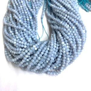 Puede incluir: Una hebra de cuentas de piedra preciosa facetadas de color azul claro. Las cuentas son pequeñas y redondas, y tienen un acabado liso y pulido.