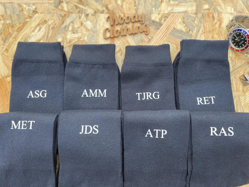 Puede incluir: Diez pares de calcetines de color gris oscuro con iniciales bordadas en blanco. Las iniciales son: ASG, AMM, TJRG, RET, MET, JDS, ATP, RAS.