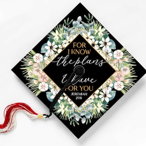 May include: Black graduation cap with a floral design and gold accents. The text "For I know the plans I have for you Jeremiah 29:11" is written on the cap.