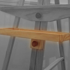 May include: A wooden shelf with a rounded edge, attached to a wooden easel. The shelf is made of light wood and has a natural finish.