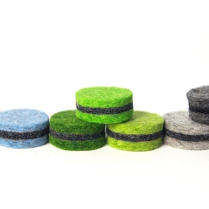 May include: A row of colorful felt circles with black trim. The circles are arranged in a rainbow pattern, starting with blue and ending with gray.