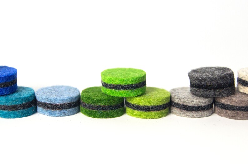 May include: A row of colorful felt circles with black trim. The circles are arranged in a rainbow pattern, starting with blue and ending with gray.