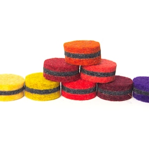 May include: A set of nine felt circles in various colors, including yellow, orange, red, purple, and burgundy. Each circle has a black band around the middle.