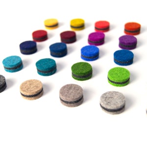 May include: Assortment of colorful felt circles with black trim. The circles are arranged in a triangular pattern on a white background.