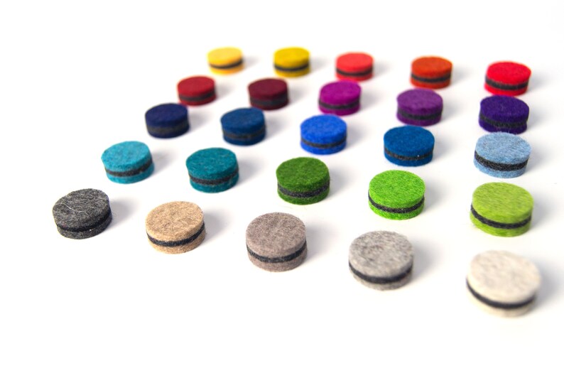 May include: Assortment of colorful felt circles with black trim. The circles are arranged in a triangular pattern on a white background.