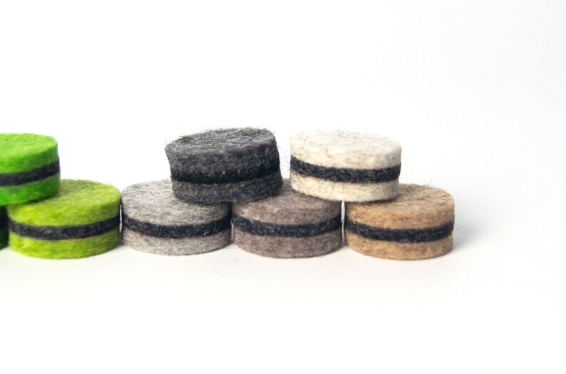 May include: A set of six felt furniture pads in various colors, including green, gray, beige, and brown. Each pad has a black felt ring around the edge.