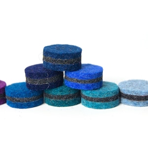 May include: A set of ten felt circles with a black stripe around the middle. The circles are arranged in a rainbow pattern, starting with purple and ending with green.