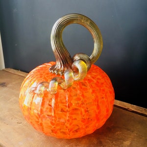 Bright orange hand blown glass pumpkin with iridescent gold stem
