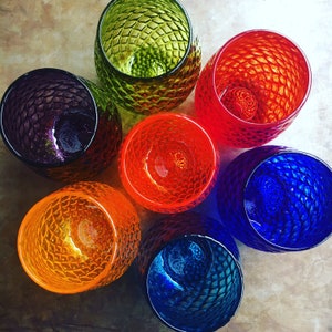 May include: Seven colorful glass tumblers with a textured, geometric pattern. The tumblers are in shades of green, red, orange, blue, and purple.