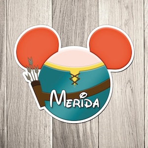 May include: A Merida-themed sticker in the shape of Mickey Mouse ears. The design features Merida's teal dress, a brown quiver with arrows, and the name "Merida" in white script. The ears are orange.