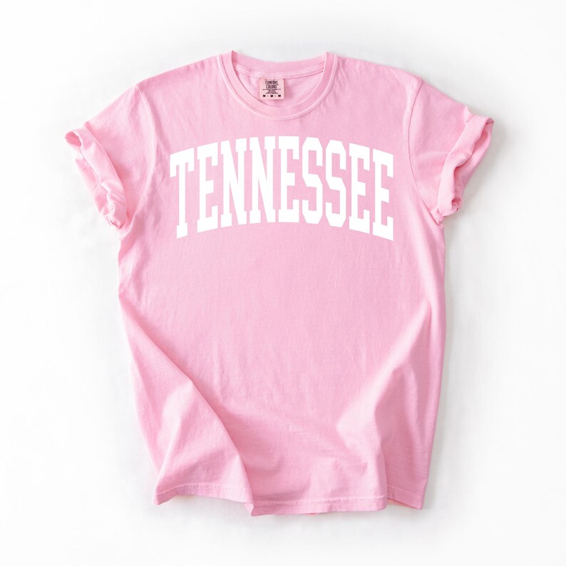 K&ouml;nnte beinhalten: Ein pinkfarbenes T-Shirt mit dem Wort "TENNESSEE" in wei&szlig; auf der Vorderseite.