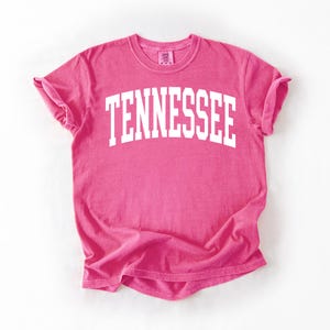 K&ouml;nnte beinhalten: Ein pinkfarbenes T-Shirt mit dem Wort "TENNESSEE" in wei&szlig; auf der Vorderseite.