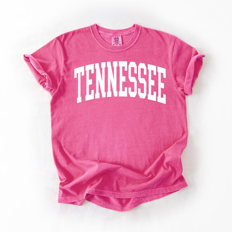 K&ouml;nnte beinhalten: Ein pinkfarbenes T-Shirt mit dem Wort "TENNESSEE" in wei&szlig; auf der Vorderseite.
