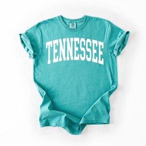 K&ouml;nnte beinhalten: Ein t&uuml;rkisfarbenes T-Shirt mit dem Wort "TENNESSEE" in Wei&szlig; auf der Vorderseite.