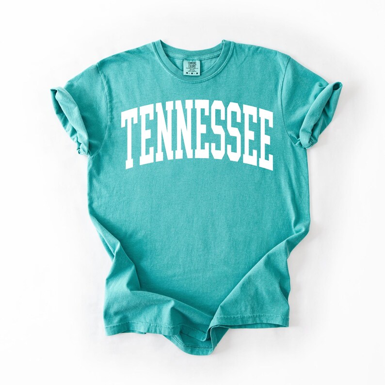 K&ouml;nnte beinhalten: Ein t&uuml;rkisfarbenes T-Shirt mit dem Wort "TENNESSEE" in Wei&szlig; auf der Vorderseite.
