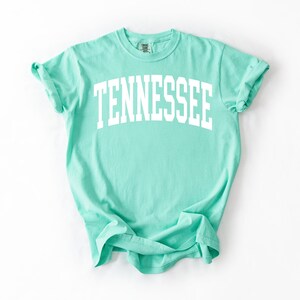 K&ouml;nnte beinhalten: Ein hellgr&uuml;nes T-Shirt mit dem Wort "TENNESSEE" in wei&szlig; auf der Vorderseite.
