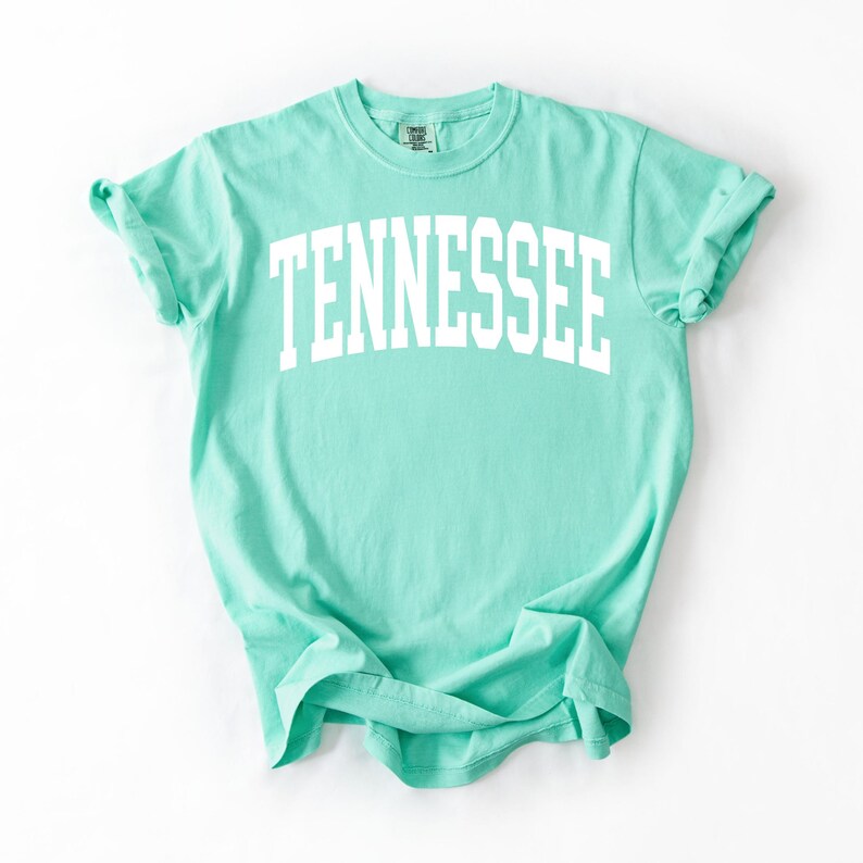 K&ouml;nnte beinhalten: Ein hellgr&uuml;nes T-Shirt mit dem Wort "TENNESSEE" in wei&szlig; auf der Vorderseite.