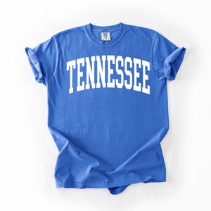 K&ouml;nnte beinhalten: Ein k&ouml;nigsblaues T-Shirt mit dem Wort "TENNESSEE" in wei&szlig; in einer Bogenform gedruckt.