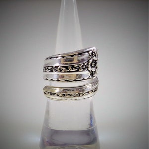 May include: A silver spoon ring with floral designs. The ring is made from a vintage spoon and is a unique piece of jewelry.
