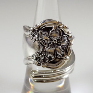May include: A silver ring made from a repurposed spoon, featuring a detailed floral design with a large flower and smaller blossoms.