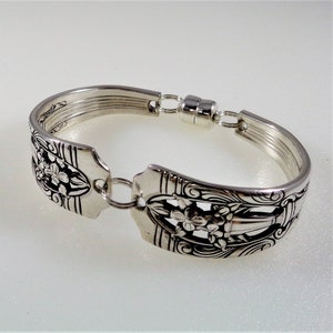 May include: A silver bracelet made from a vintage spoon with a floral design. The bracelet has a magnetic clasp.