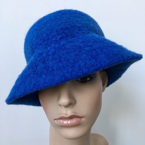 May include: A bright blue felt hat with a wide brim. The hat is sitting on a mannequin's head.