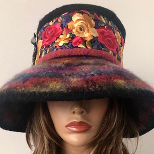 May include: A wide-brimmed black felt hat with a colorful embroidered band featuring floral designs in shades of red, yellow, and purple.