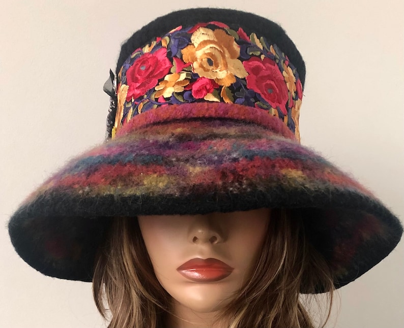 May include: A wide-brimmed black felt hat with a colorful embroidered band featuring floral designs in shades of red, yellow, and purple.