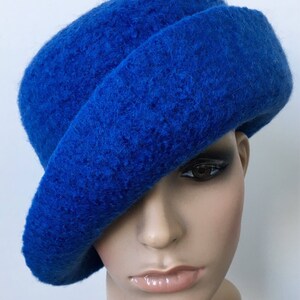 May include: A bright blue felt hat with a wide brim, angled to the side. The hat is made of a soft, fuzzy material.