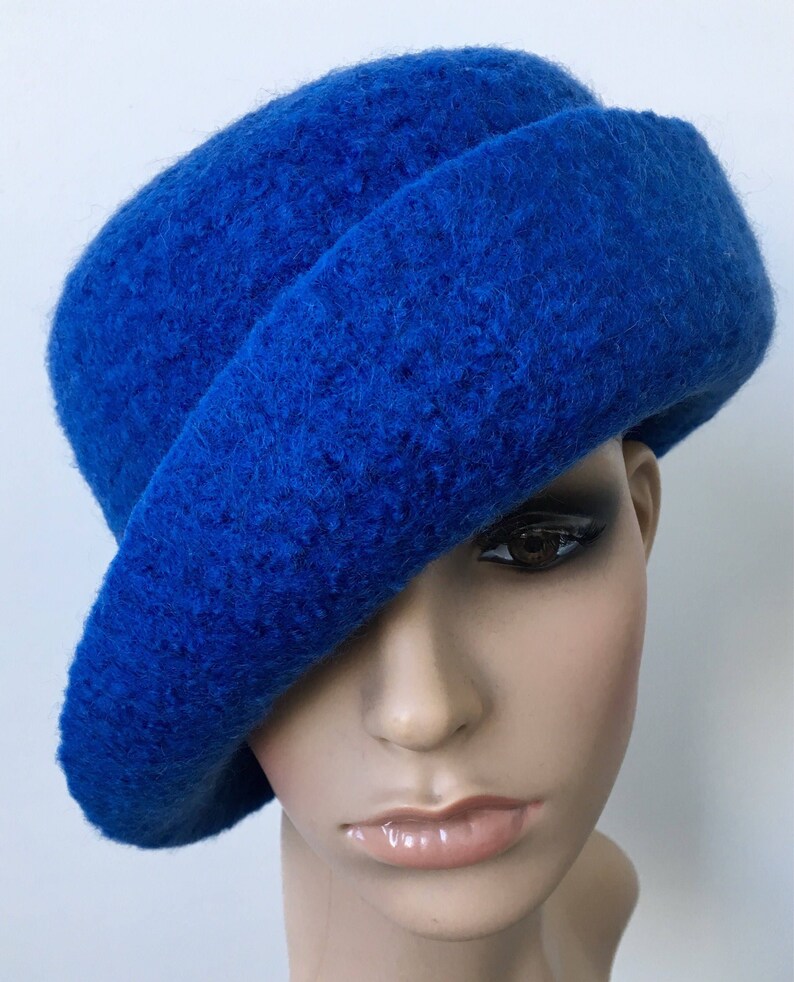May include: A bright blue felt hat with a wide brim, angled to the side. The hat is made of a soft, fuzzy material.