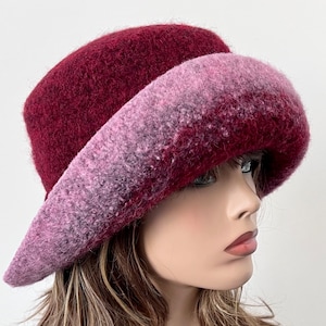 May include: A burgundy felt hat with a wide brim, featuring a gradient of pink and purple hues.