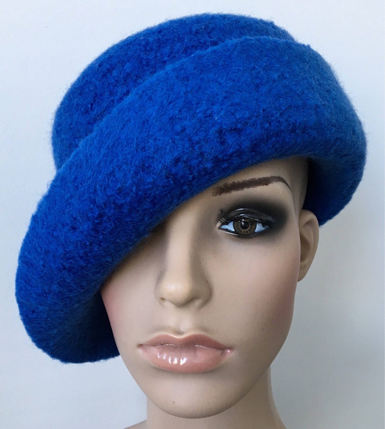 May include: A bright blue felt hat with a wide brim, angled to the side. The hat is made of a soft, fuzzy material.