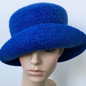 May include: A bright blue felt hat with a wide brim. The hat is made of a soft, fuzzy material and has a simple, classic design.