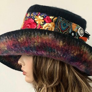 May include: A wide-brimmed black felt hat with a colorful embroidered band and a silver charm. The brim is dyed in a rainbow of colors.