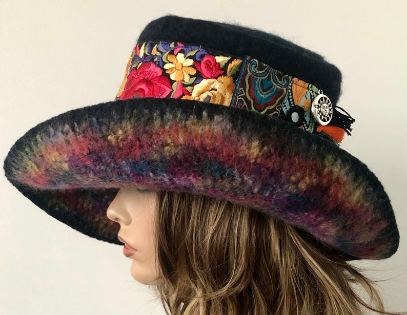 May include: A wide-brimmed black felt hat with a colorful embroidered band and a silver charm. The brim is dyed in a rainbow of colors.