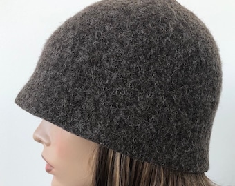 May include: A brown felt cloche hat with a wide brim. The hat is made of a soft, fuzzy material and has a simple, classic design.