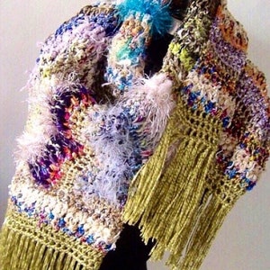 May include: A colorful crocheted shawl with a variety of textures and colors, including purple, pink, blue, green, and white. The shawl has long, gold fringe and a fluffy white trim.